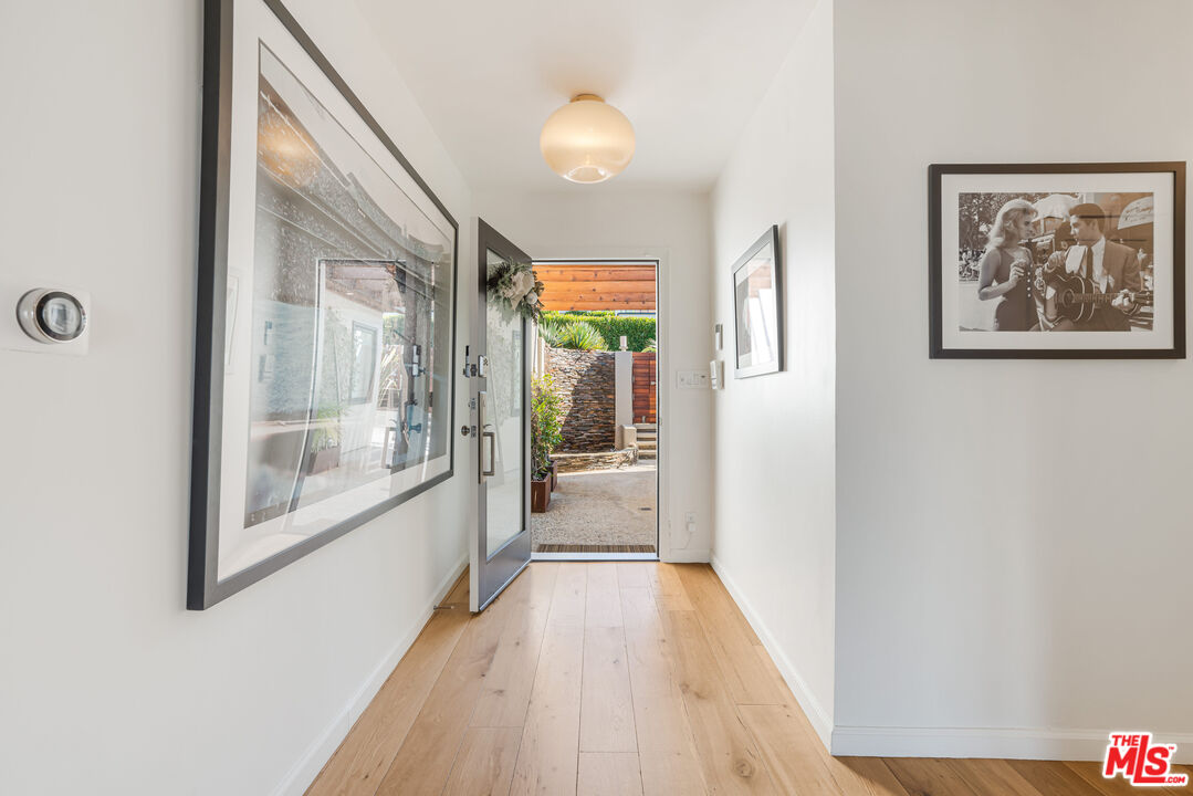 245 Tranquillo Road Pacific Palisades, CA 90272 - Photo 7 of 45 a view of a hallway with wooden floor and a floor to ceiling window