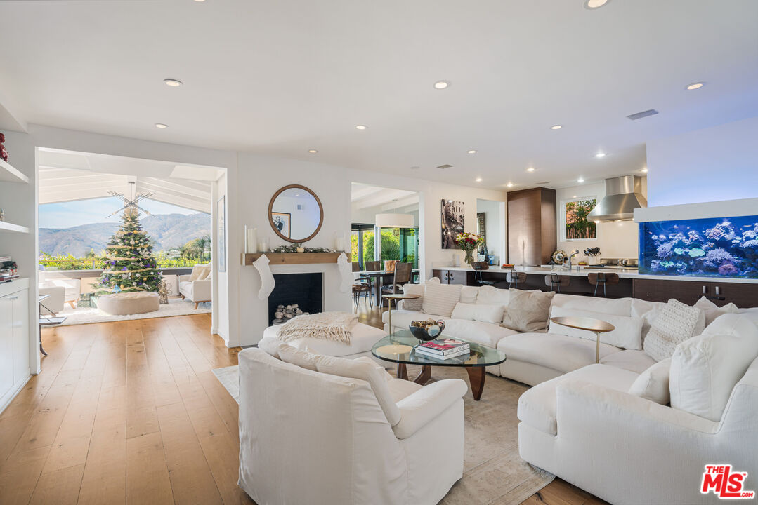 245 Tranquillo Road Pacific Palisades, CA 90272 - Photo 8 of 45 a living room with furniture a fireplace and a dining table with wooden floor