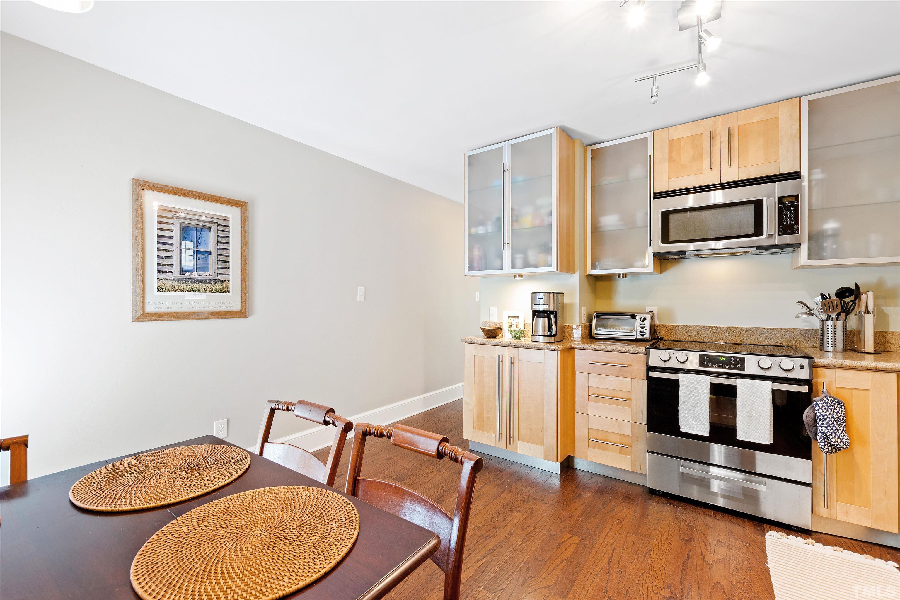 2526 Noble Road Raleigh, NC 27608 - Photo 13 of 27 a kitchen with stainless steel appliances a stove a sink cabinets and a dining table