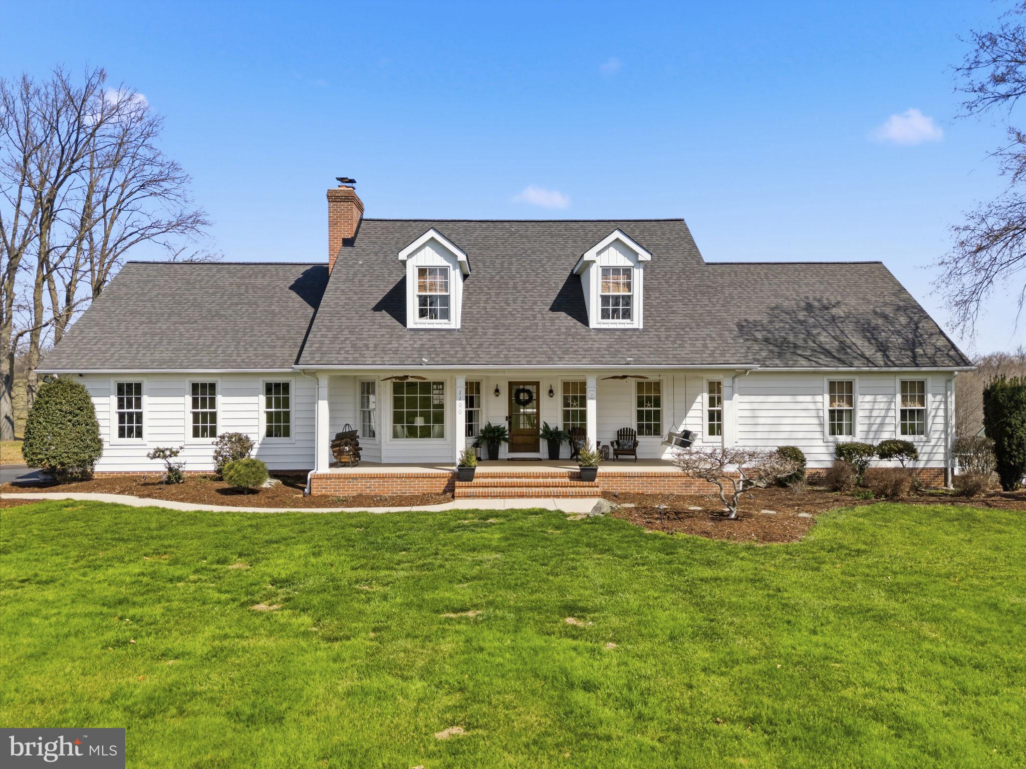 a front view of a house with a garden and trees