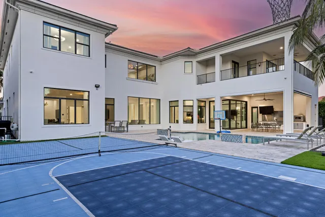 a front view of a house with a garden and palm trees
