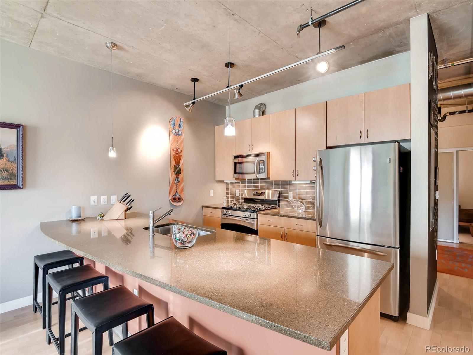 2229 Blake Street, Unit 506 Denver, CO 80205 - Photo 10 of 29 a kitchen with kitchen island a table chairs refrigerator and microwave