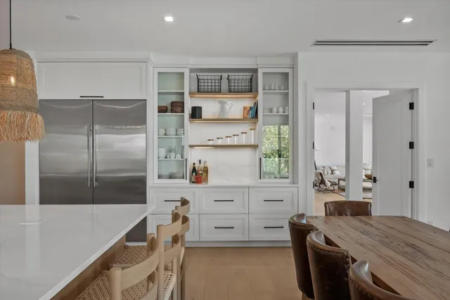 a backyard of a house with table and chairs under a large tree