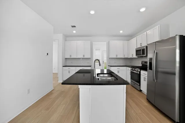 a kitchen with granite countertop a refrigerator sink and cabinets