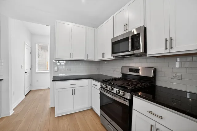 a kitchen with stainless steel appliances white cabinets and a stove a oven with wooden floor