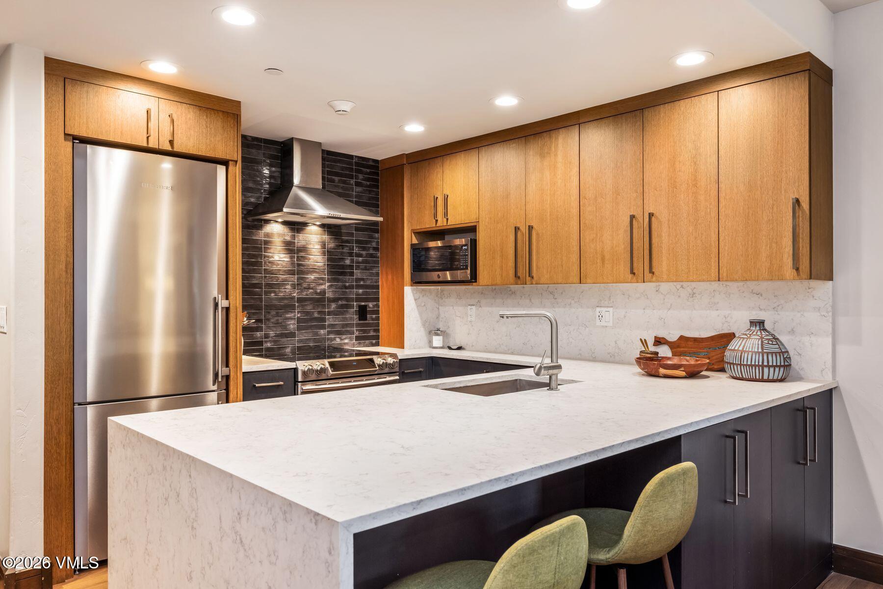 30 Cresta Road, Unit 202 Edwards, CO 81632 - Photo 7 of 23 a kitchen with stainless steel appliances a table chairs in it and wooden cabinets