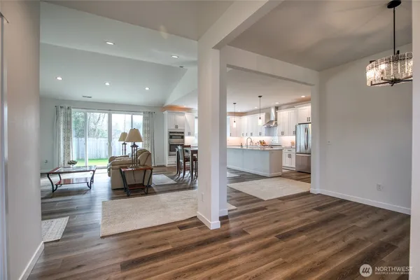 a living room with furniture a dining table and kitchen view with wooden floor