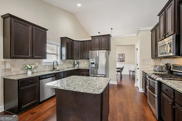 a kitchen with granite countertop a sink cabinets and stainless steel appliances