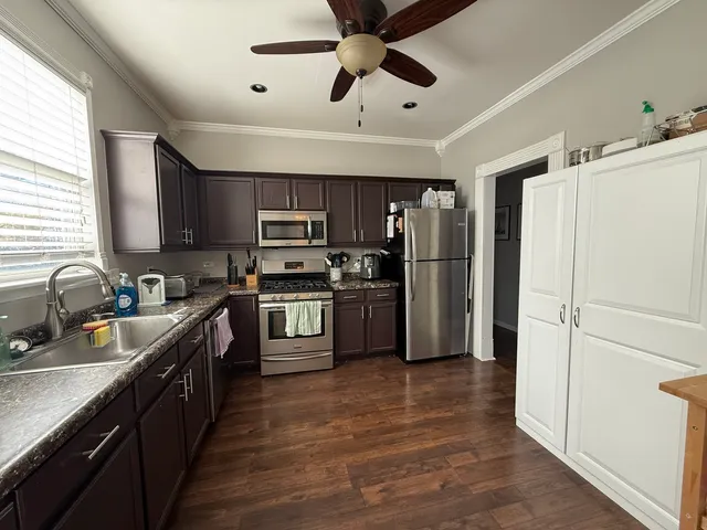 a kitchen with kitchen island stainless steel appliances cabinets a sink and a window