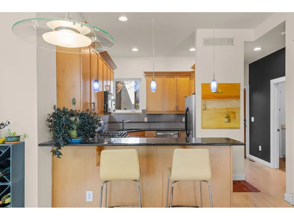 a kitchen with stainless steel appliances granite countertop a refrigerator a stove and a sink with wooden floor