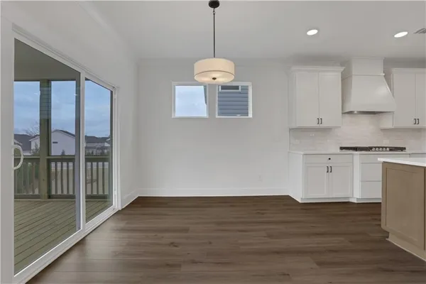 a view of an empty room with wooden floor and a ceiling fan