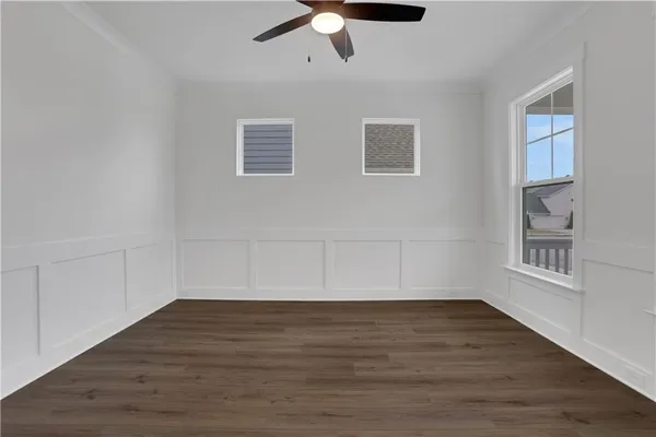 an empty room with wooden floor a ceiling fan a fireplace and windows
