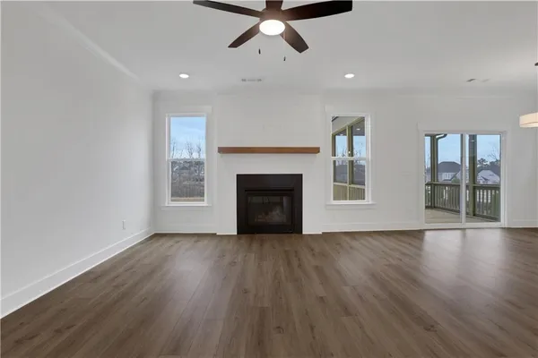 a view of an empty room with wooden floor and a ceiling fan