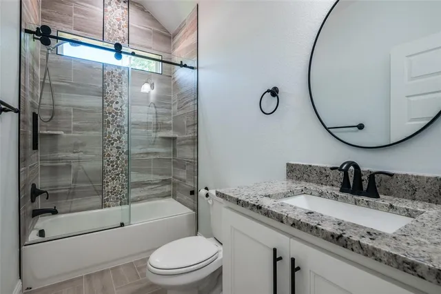 a bathroom with a granite countertop sink toilet and shower