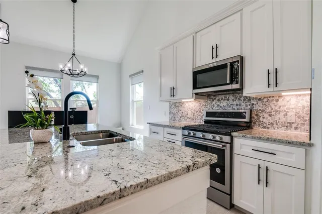 a kitchen with stainless steel appliances granite countertop a sink stove and cabinets