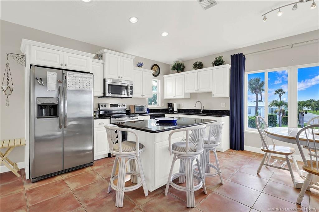 10701 South Ocean Drive, Unit 855 Jensen Beach, FL 34957 - Photo 16 of 67 a kitchen with stainless steel appliances granite countertop a stove a refrigerator a sink a table and chairs