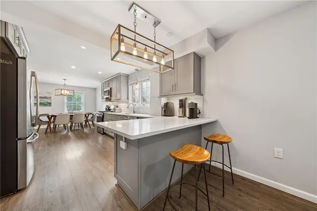 a kitchen with stainless steel appliances granite countertop a table chairs and a wooden floor