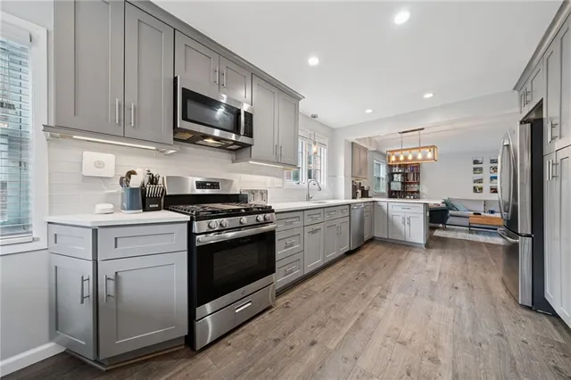 a kitchen with stainless steel appliances kitchen island granite countertop a sink cabinets and wooden floor