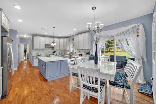 a large kitchen with kitchen island a chandelier and a view of living room