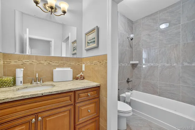 a bathroom with a granite countertop sink a toilet a mirror a bathtub and shower