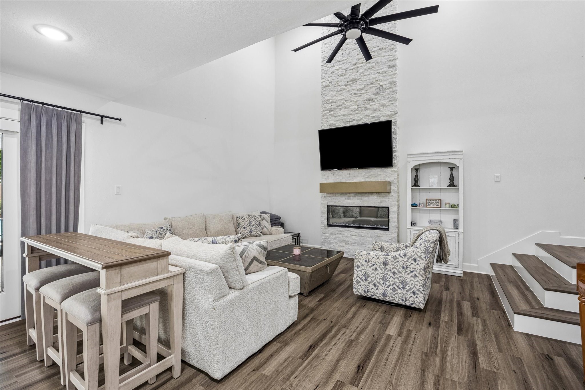 1420 Indiana Street Houston, TX 77006 - Photo 9 of 31 This modern living room features high ceilings, a sleek ceiling fan, and a striking stone fireplace.