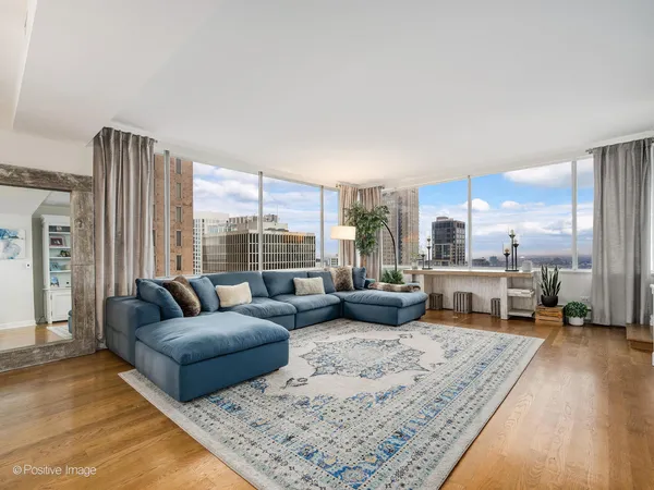 a living room with furniture large windows and wooden floor