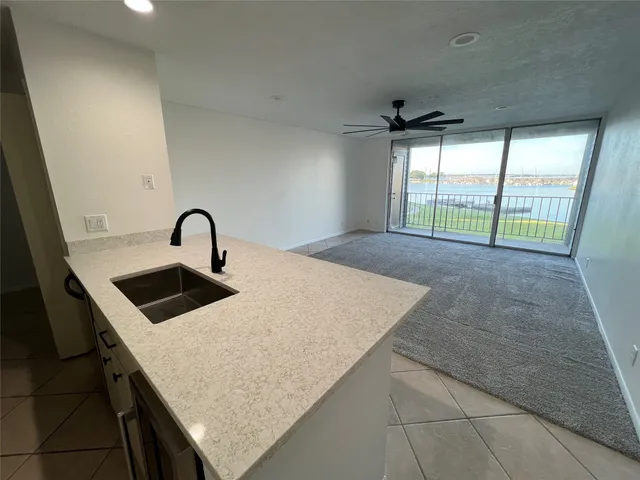 a kitchen with a sink a counter top space and a ceiling fan