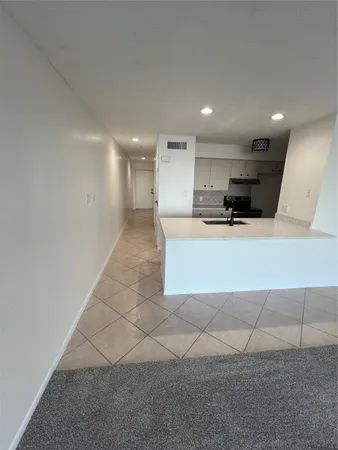 a large white kitchen with a sink and a large mirror
