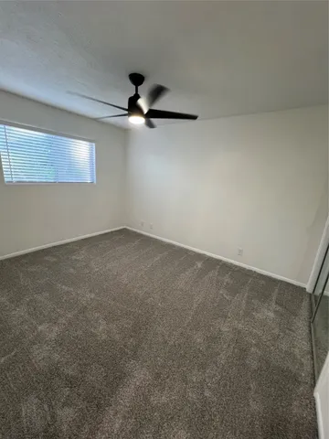 an empty room with a ceiling fan and a window