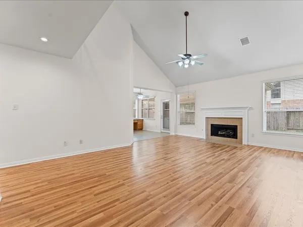 a view of an empty room with wooden floor fireplace and a window