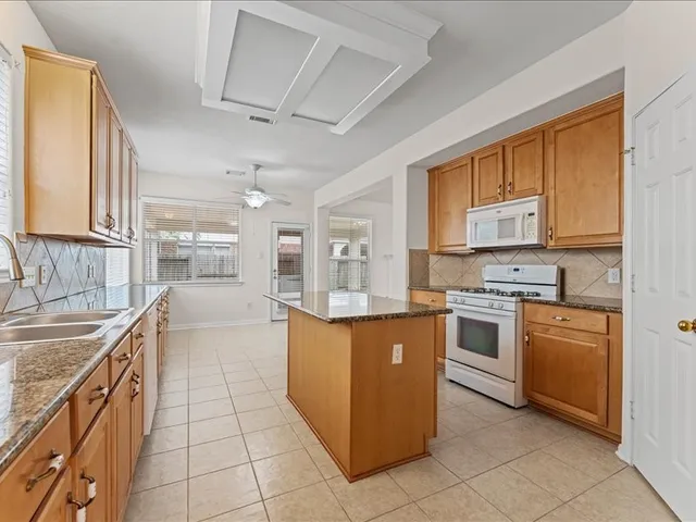 a kitchen with stainless steel appliances granite countertop a stove top oven a sink a counter top space and cabinets