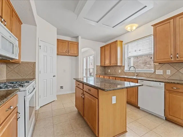 a kitchen with stainless steel appliances granite countertop a stove a sink and a refrigerator