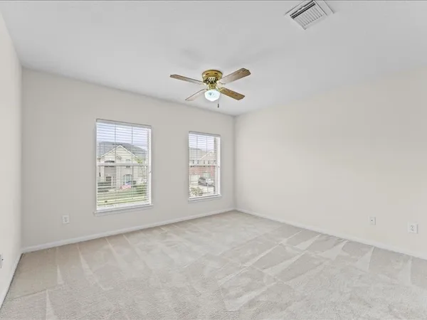 an empty room with chandelier fan and windows