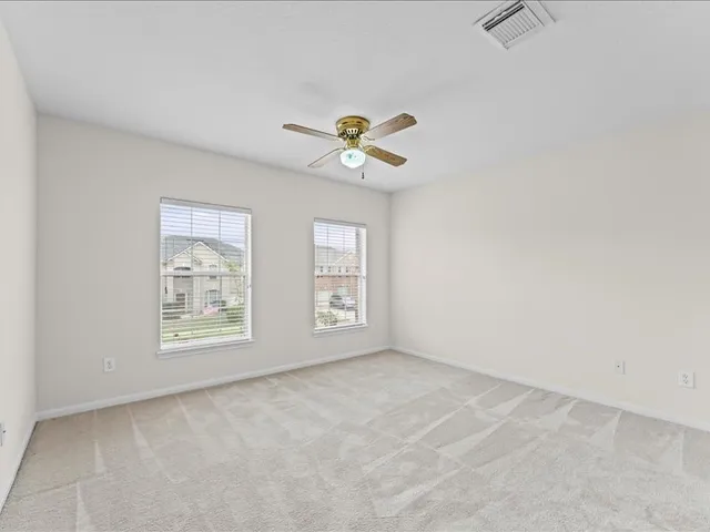 an empty room with chandelier fan and windows