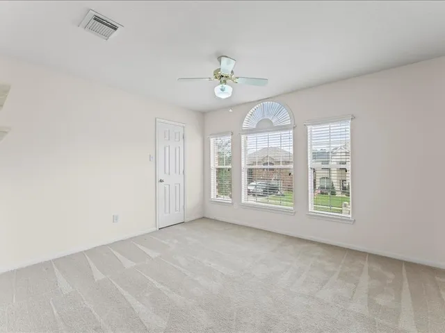 an empty room with windows ceiling fan and windows
