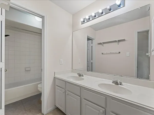 a bathroom with a tub a double vanity sink and mirror