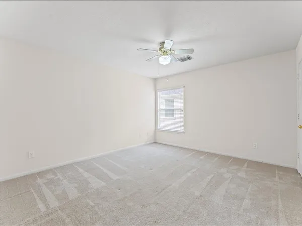an empty room with a chandelier fan and windows