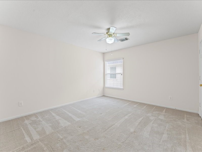3323 Sainte Mere Eglise Lane Spring, TX 77388 - Photo 30 of 33 an empty room with a chandelier fan and windows