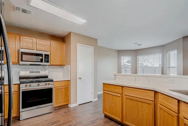 a kitchen with stainless steel appliances granite countertop a stove a sink and a microwave