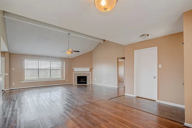 an empty room with wooden floor cabinet and windows