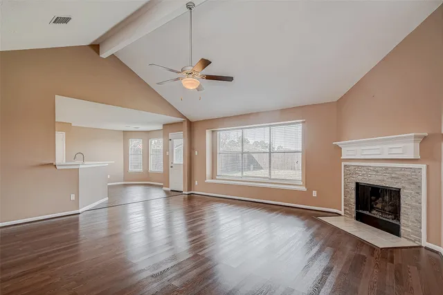 a view of an empty room with a fireplace and wooden floor