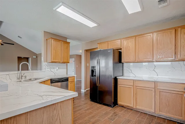 a kitchen with stainless steel appliances granite countertop a refrigerator a sink a stove and white cabinets with wooden floor