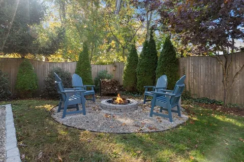 a view of a backyard with lawn chairs potted plants and tree