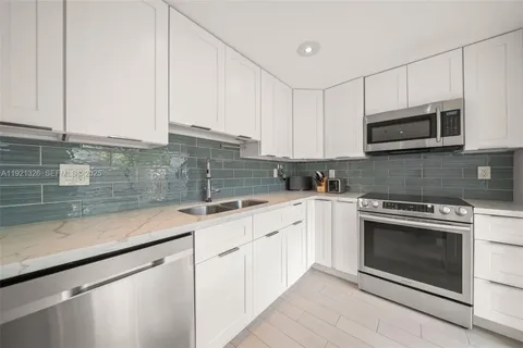 a kitchen with granite countertop white cabinets stainless steel appliances and a sink