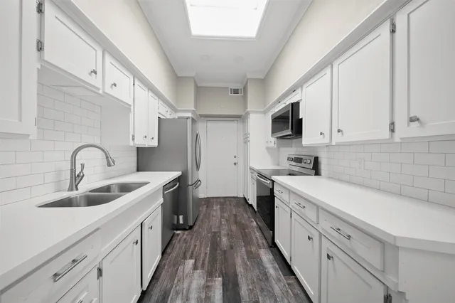 a kitchen with white cabinets sink and stainless steel appliances