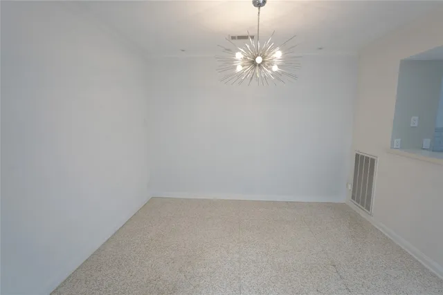 a view of an empty room with a chandelier fan