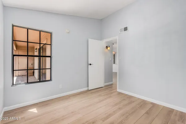 an empty room with wooden floor and windows