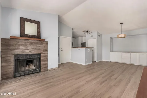 a view of empty room with kitchen and fireplace