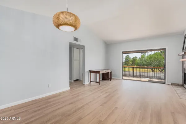 a view of empty room with wooden floor and fan