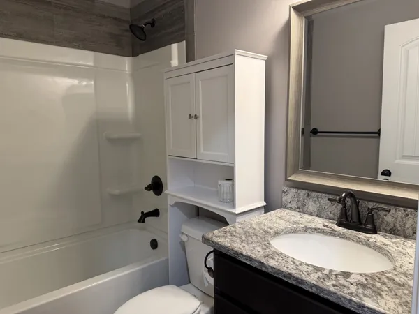 a bathroom with a granite countertop sink toilet and shower